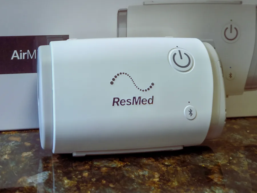 ResMed AirMini, CPAP compacto para viagens, ao lado da caixa do produto